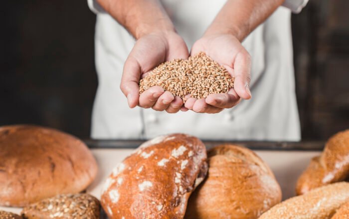 Baker Con Granos De Trigo En Las Manos Frente Pan Horneado