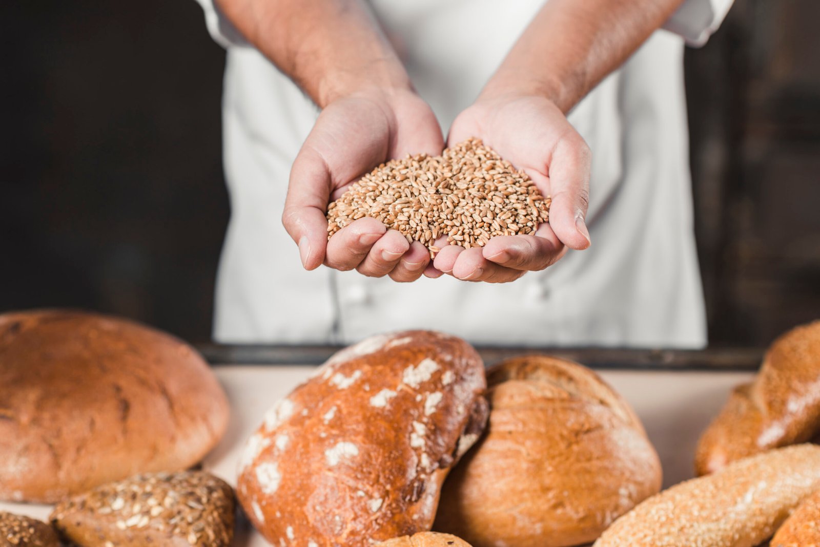 Baker Con Granos De Trigo En Las Manos Frente Pan Horneado